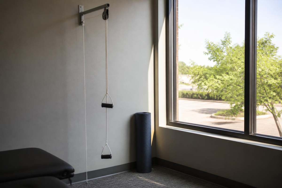 Shoulder pulley exercise device mounted near a bright clinic window