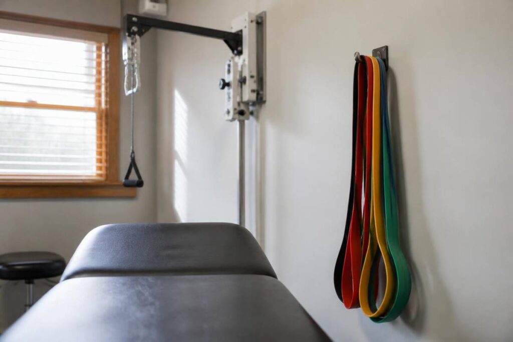 Bright physical therapy treatment area with resistance bands and a padded table