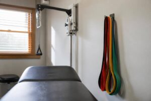 Bright physical therapy treatment area with resistance bands and a padded table